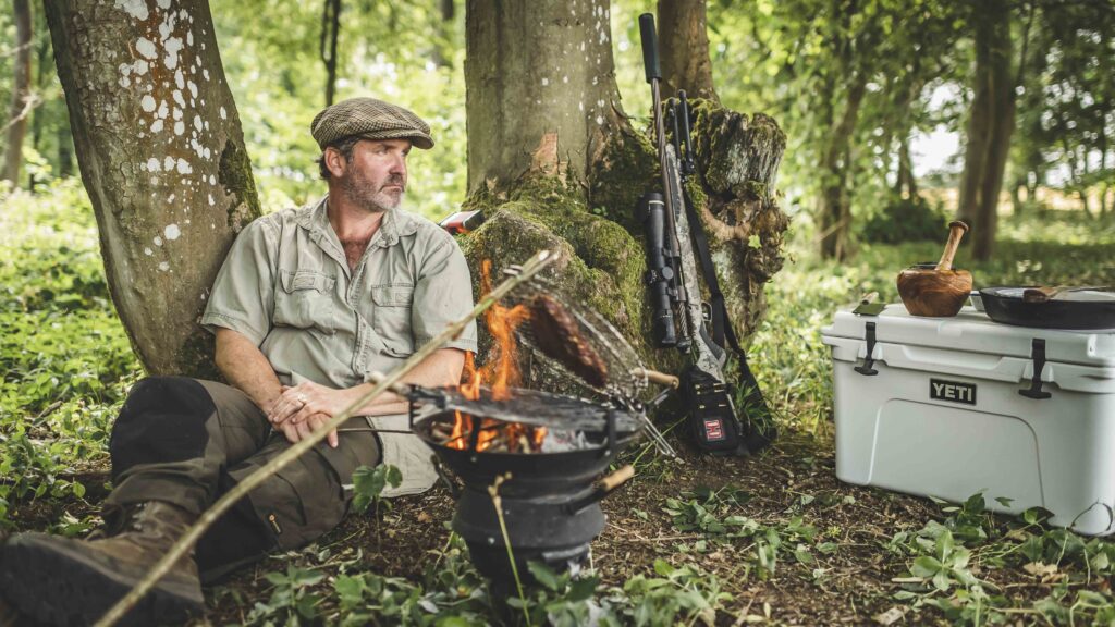 Image of a man next to a fire cooking food.