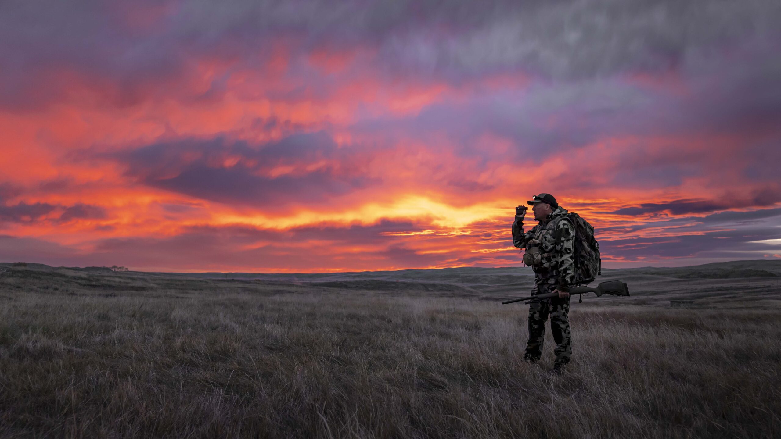 Image of a man with a spotting scope in the sunset.